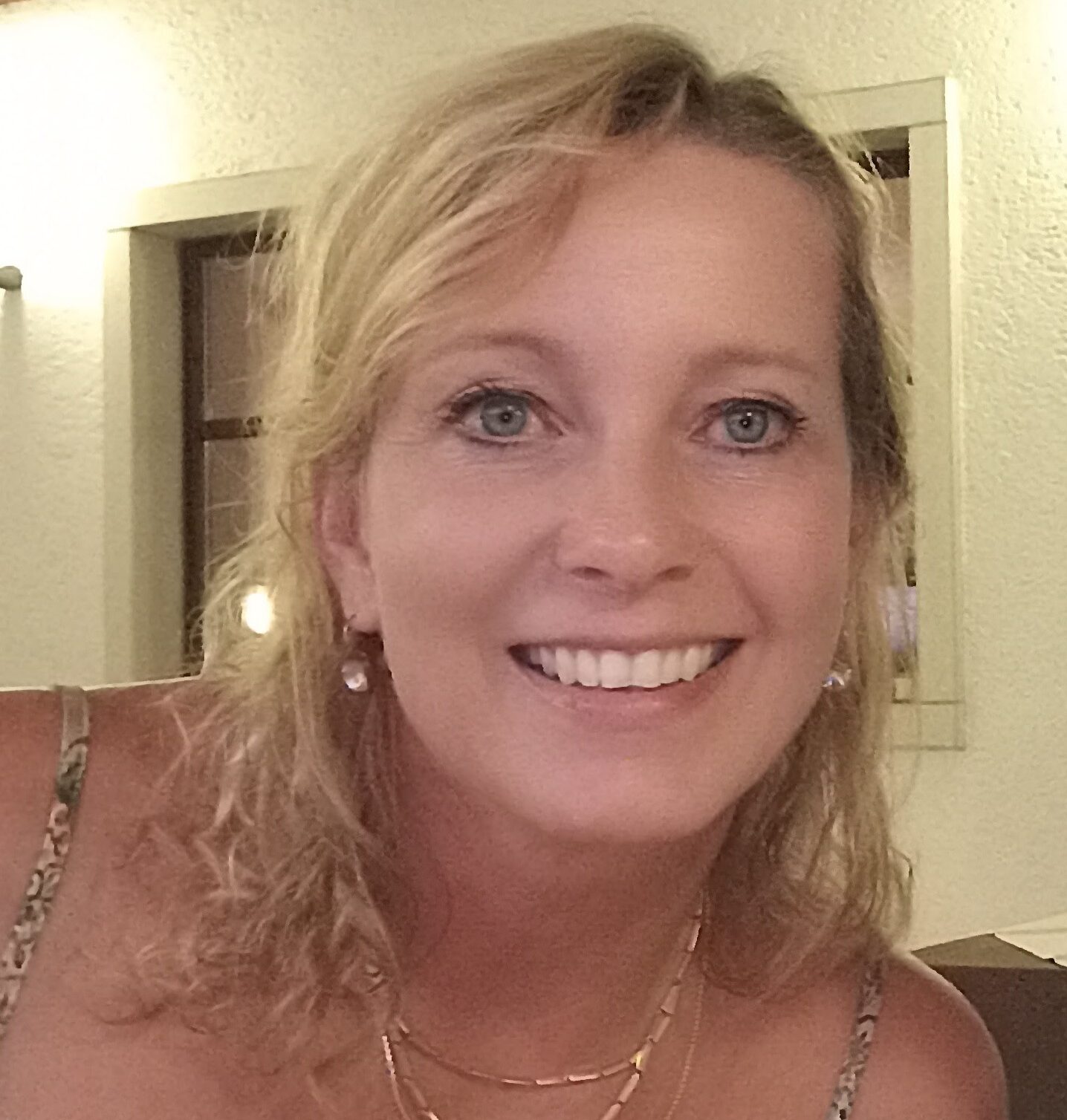 Elke, 55, steht in einem schlichten, sommerlichen Oberteil seitlich zur Kamera, ihre Haltung wirkt entspannt und natürlich.